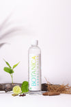 Bottle of Botanica Herbal Water with herbs and a lime on a white background